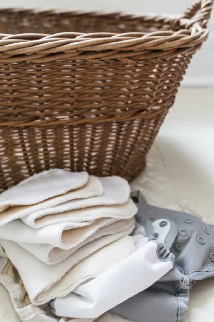 DIY cloth diaper inserts stacked up next to a wicker woven laundry basket