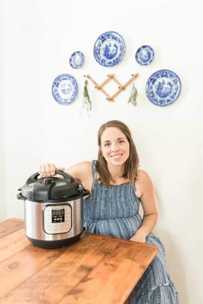 women sitting at a table with her hand touching the lid of the lid of the Instant Pot