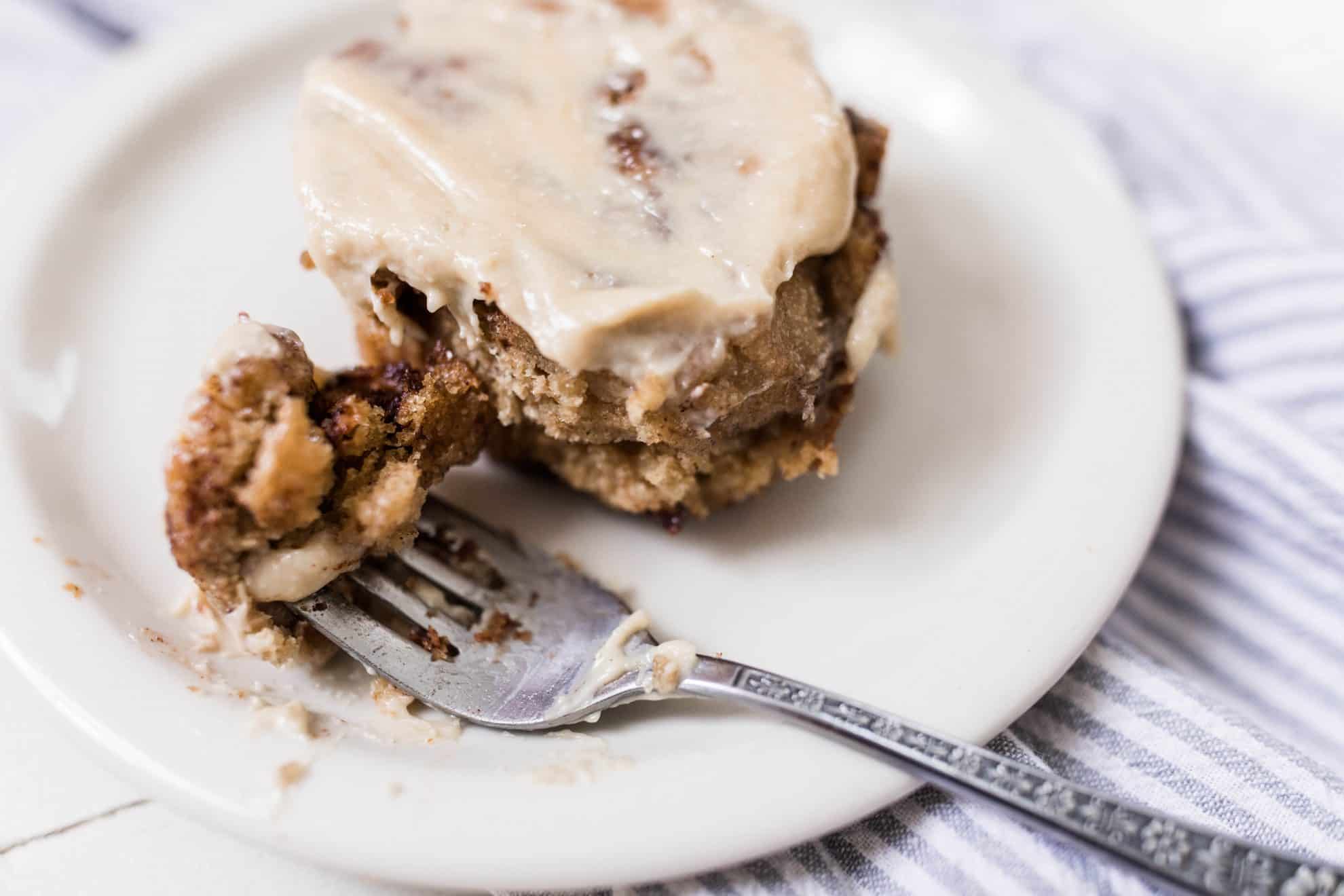 overhead photo of sourdough cinnamon rolls in a cast iron skillet on top of a white and black stripped towel on a white quartz countertop