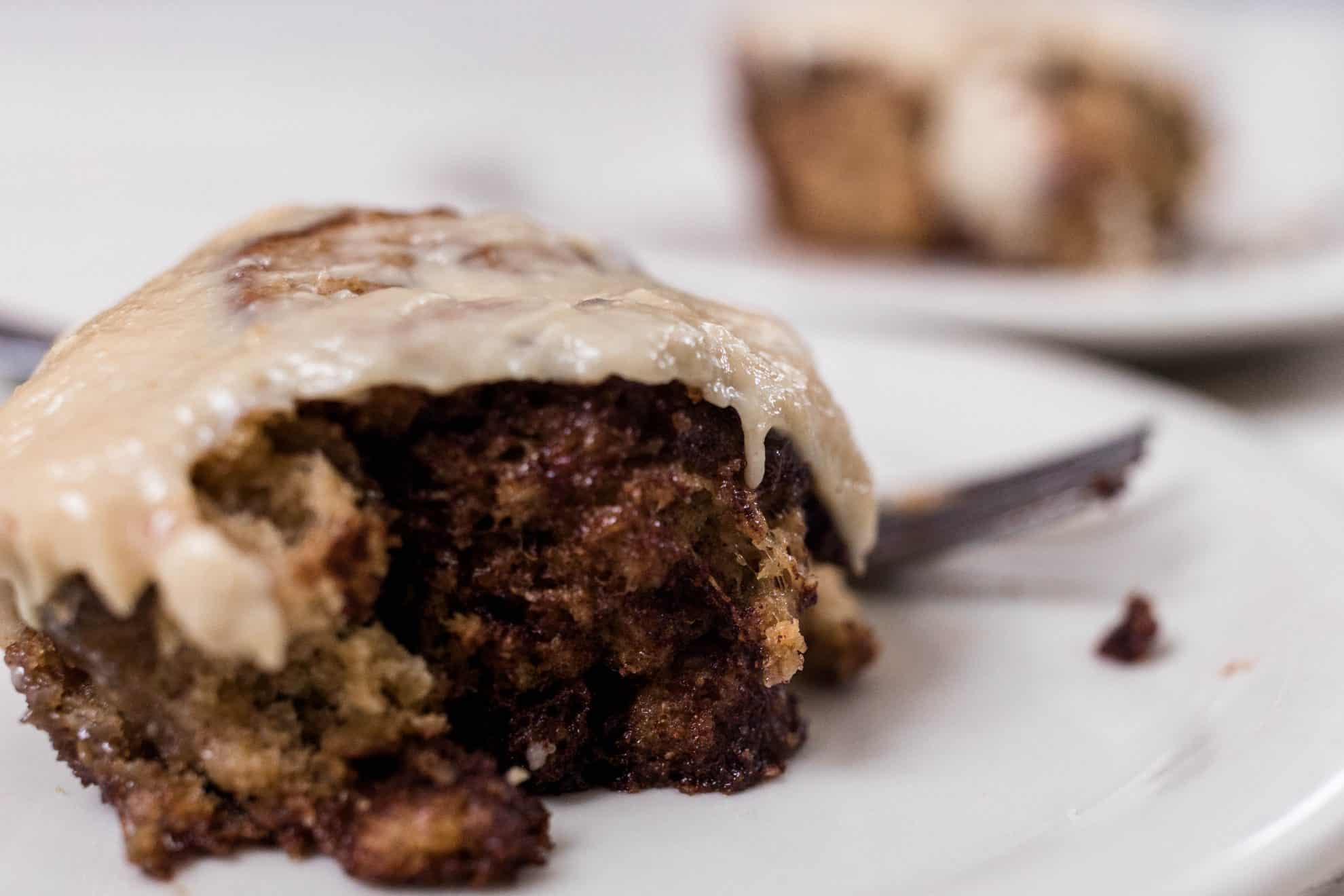 overhead photo of sourdough cinnamon rolls in a cast iron skillet on a white and black stripped towel on a white quartz countertop