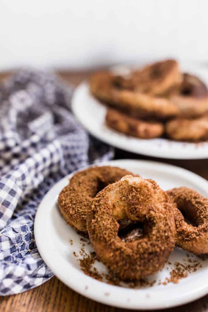 two white plates with sourdough donuts stacked onto them wiht a blue and white towel to the left