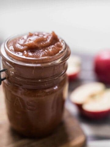 apple butter in mason jars with apples in the background