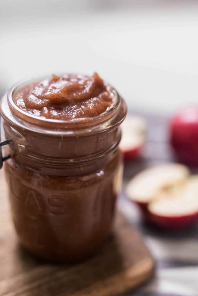 apple butter in mason jars with apples in the background