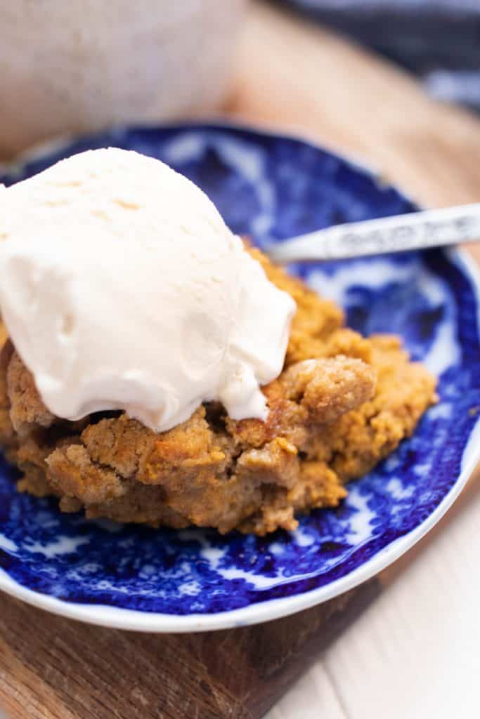antique white and blue plate with a slice of pumpkin cobbler with a large scoop of ice cream