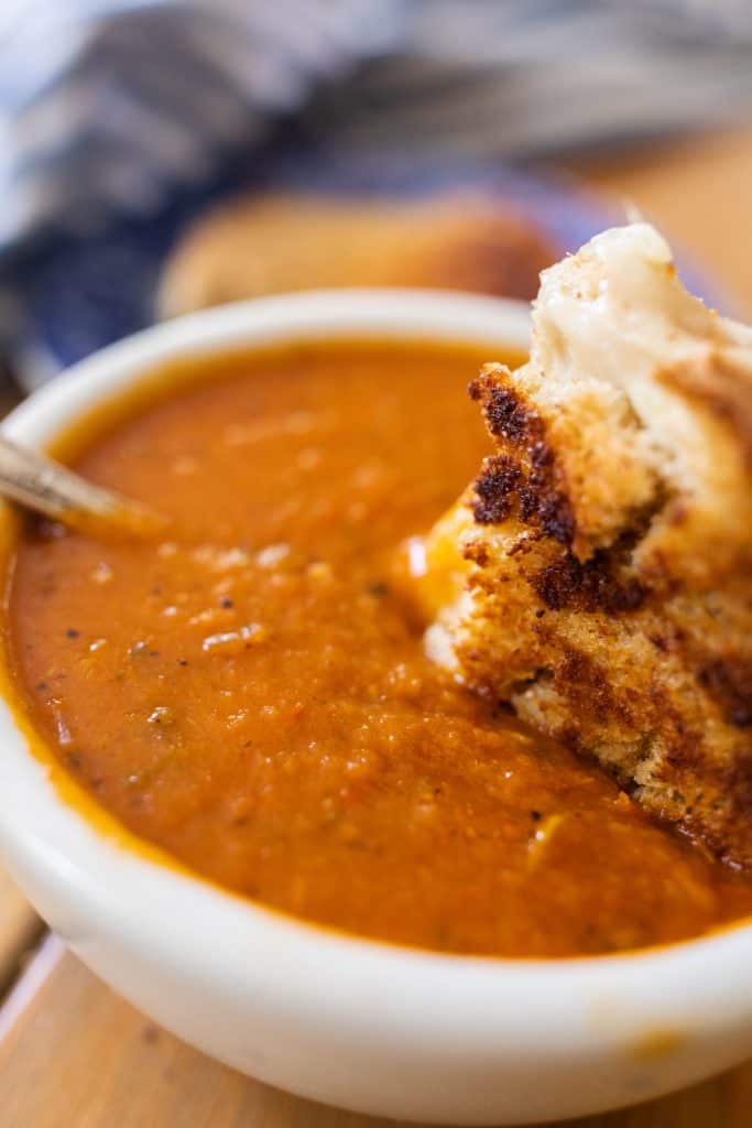 homemade grilled cheese made with sourdough bread dipped into roasted red pepper and tomato soup 