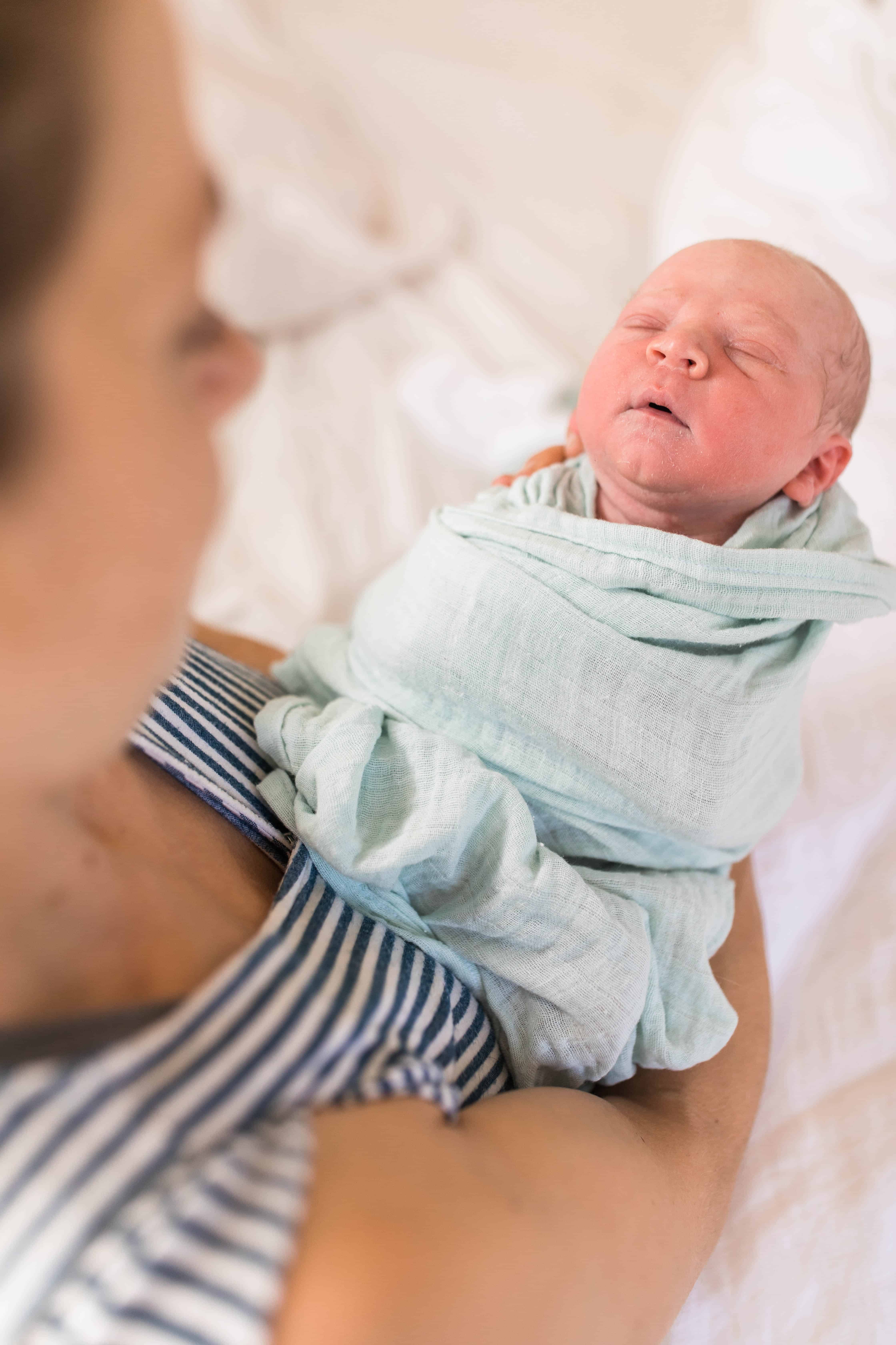 newborn baby in teal swaddle blanket