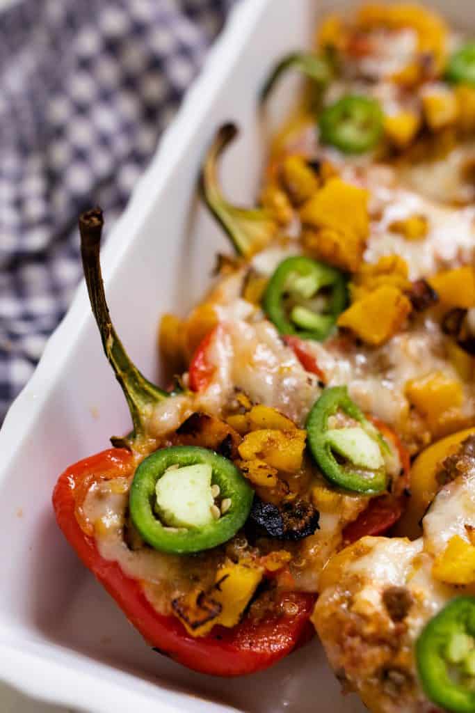 baking dish full of stuffed bell peppers with ground beef and topped with cheese and jalepenos