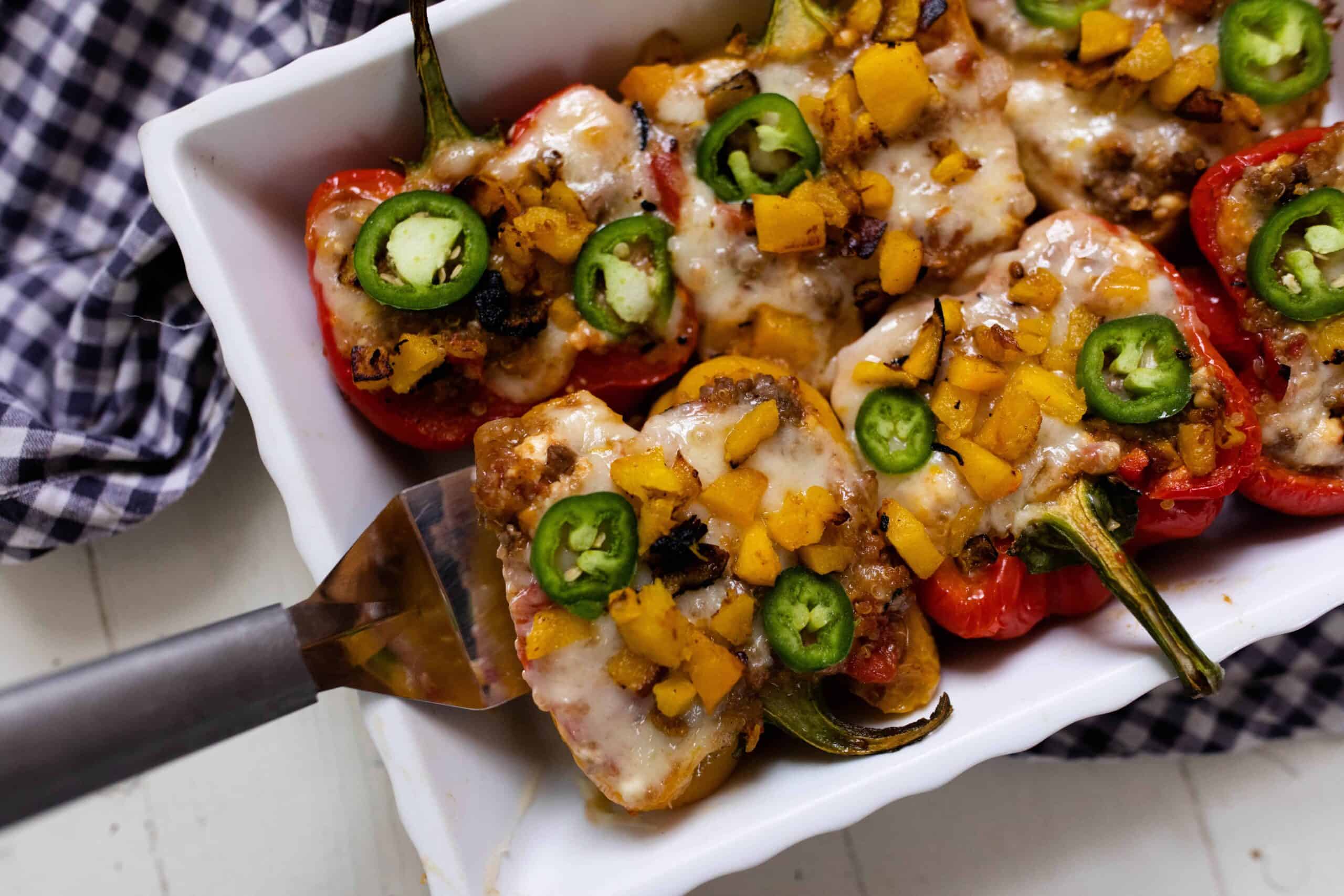 baking dish full of stuffed bell peppers with ground beef, covered in melted cheese and topped with sliced jalapenos.