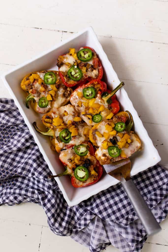 baking dish full of stuffed bell peppers on top of a blue and white towel