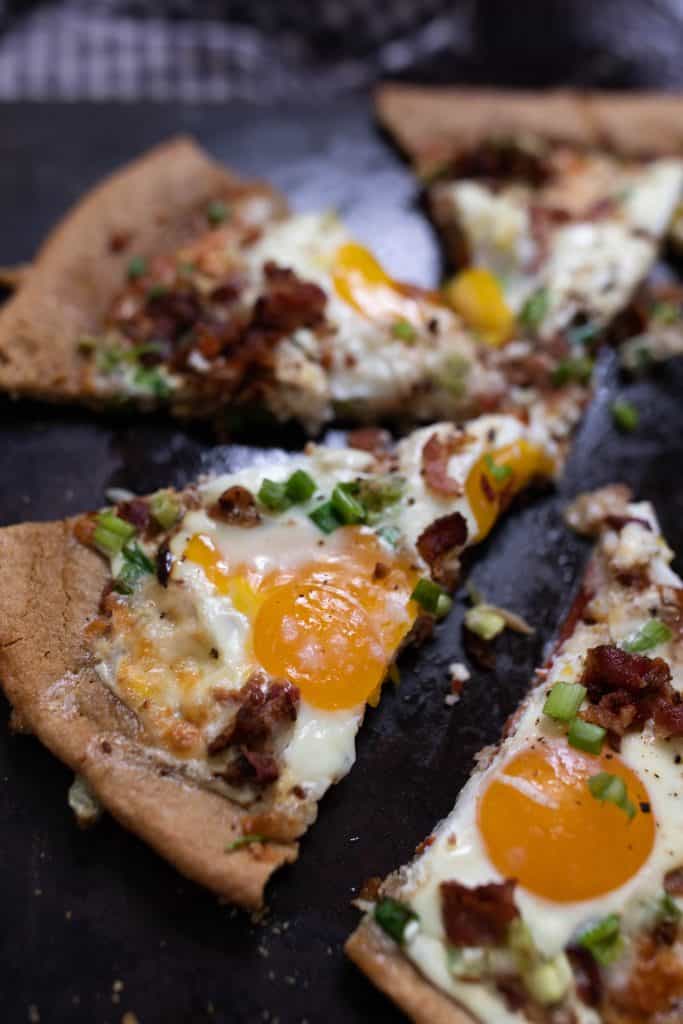 slices of breakfast pizza topped with bacon and eggs