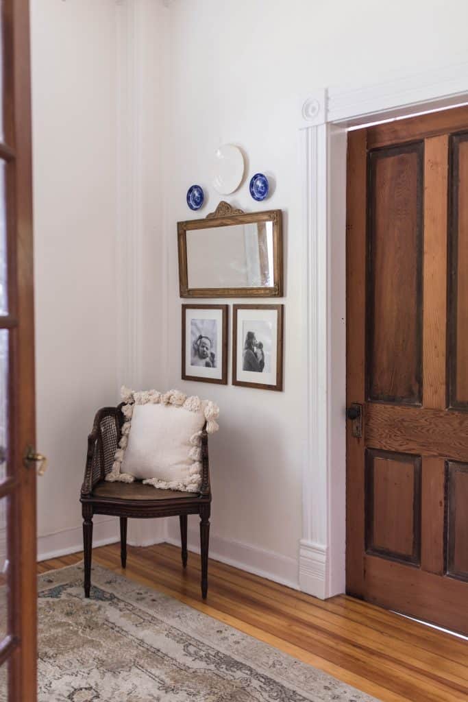 antique mirror with two family pictures hanging below it with a antique chair beside it