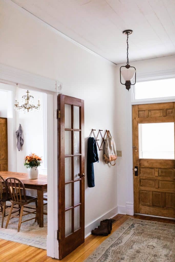 Farmhouse entryway with wood French door, Turkish rug, and antique hat rack