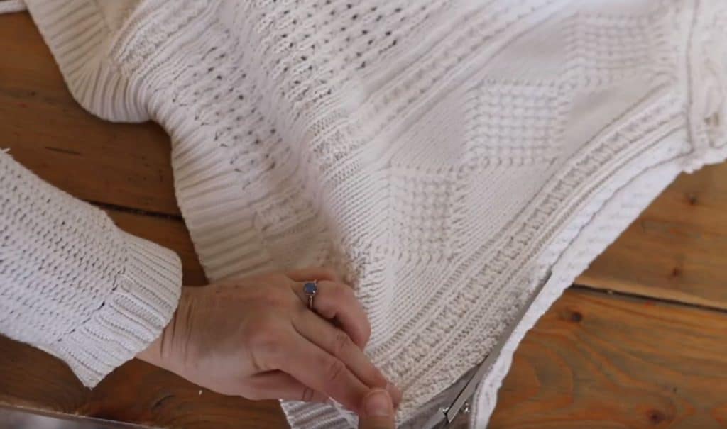 women cutting out a square of a thrifted sweater to make into a pillow