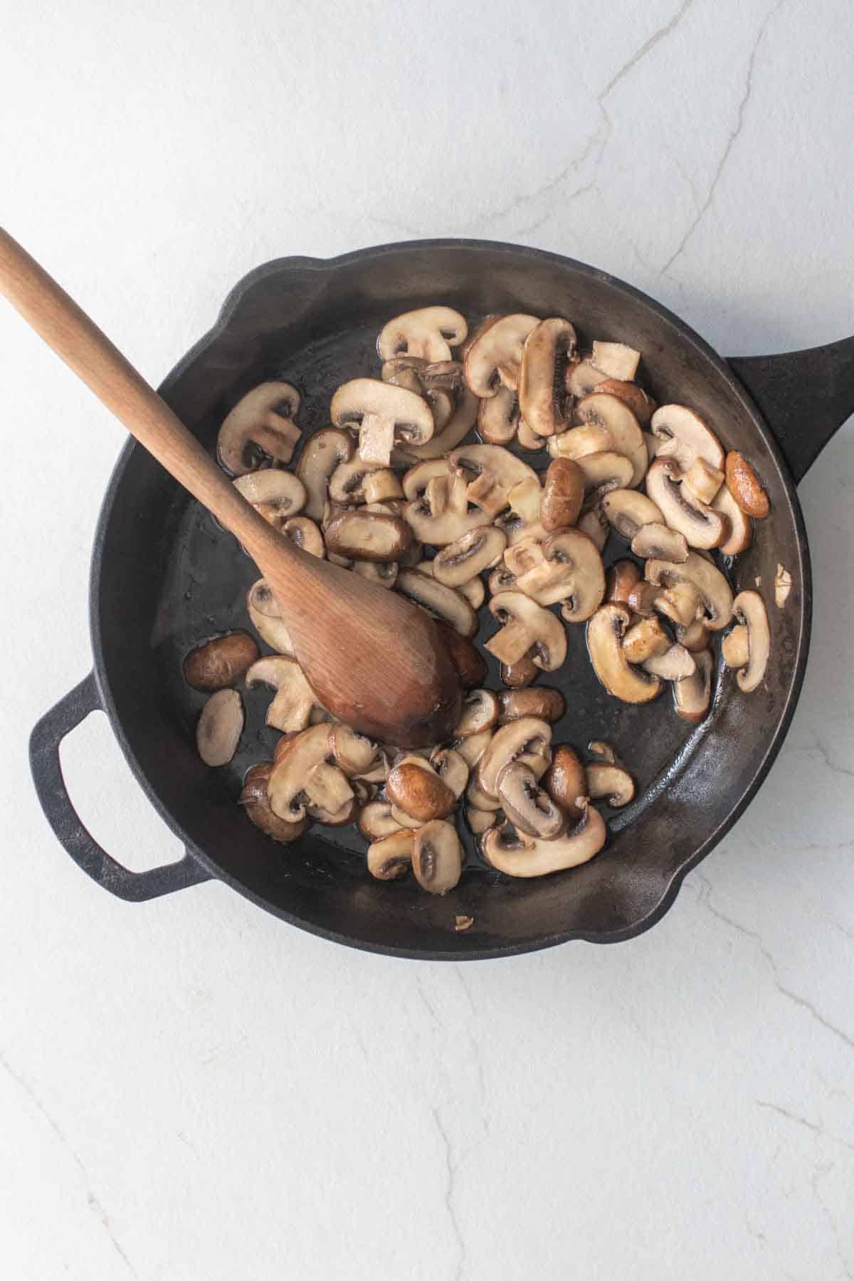 Sliced mushrooms in a cast iron skillet.