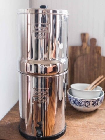 Berkey water filter system on a wood table with bowls and cutting boards in the background