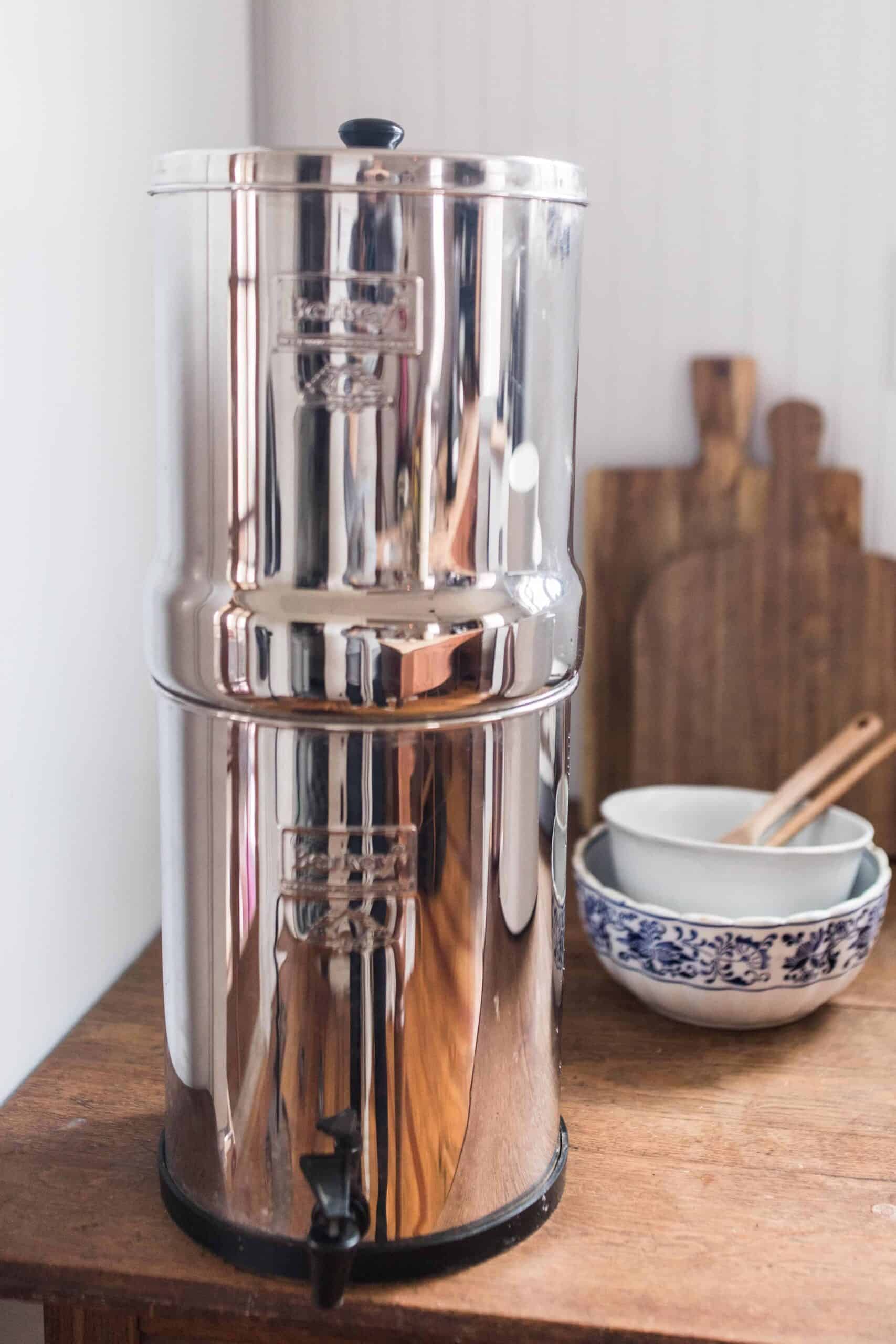 Berkey water filter system on a wood table with bowls and cutting boards in the background