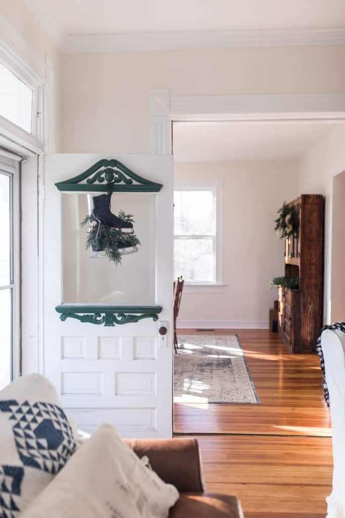 white and green antique door with black ice skates and greenery hung as a festive holiday touch