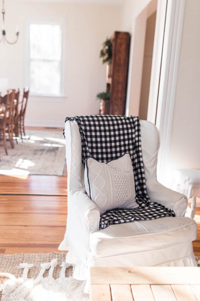 winged back chair covered in a blue and white checked flannel blanket and topped with a sweater pillow
