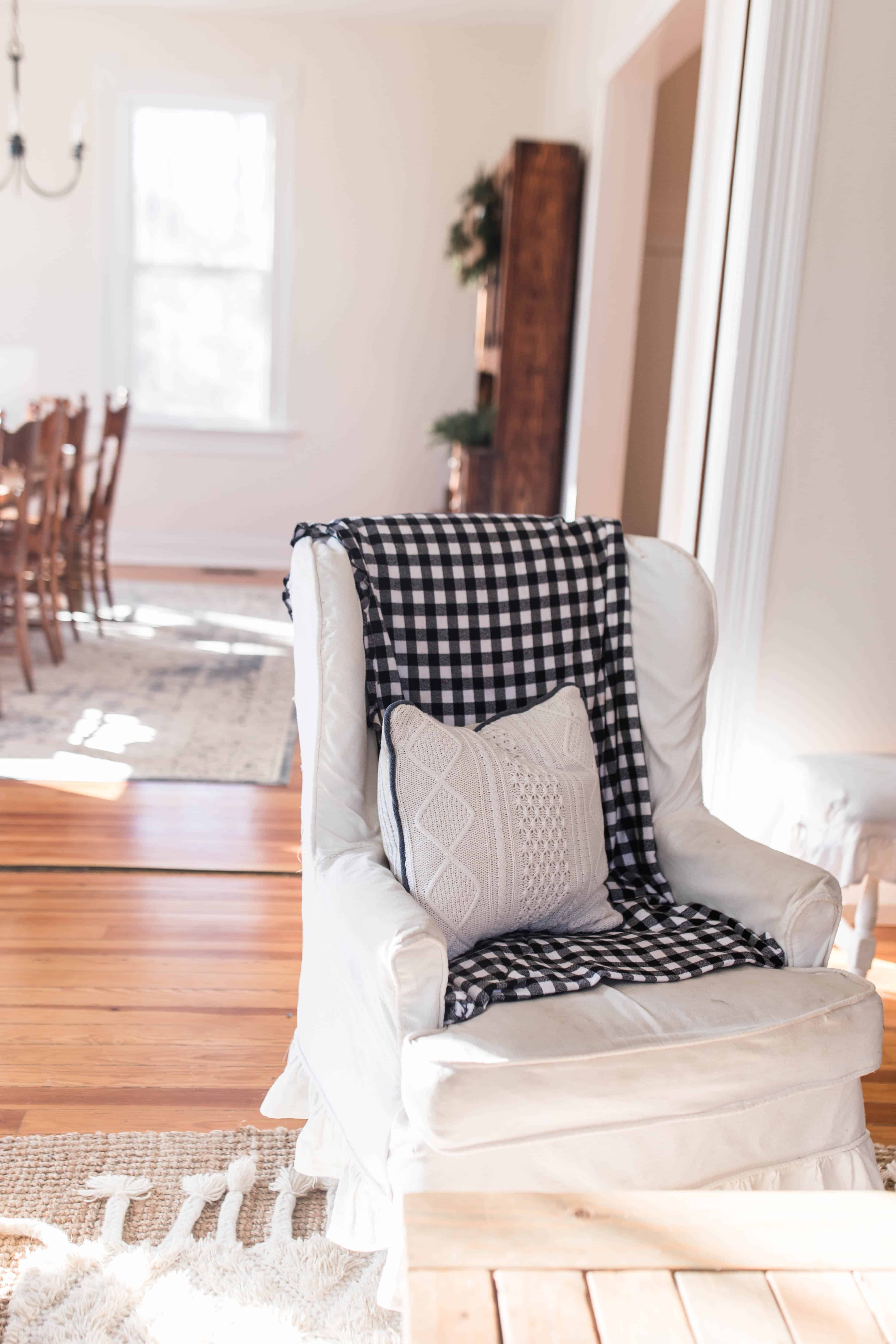 winged back chair covered in a blue and white checked flannel blanket and topped with a sweater pillow