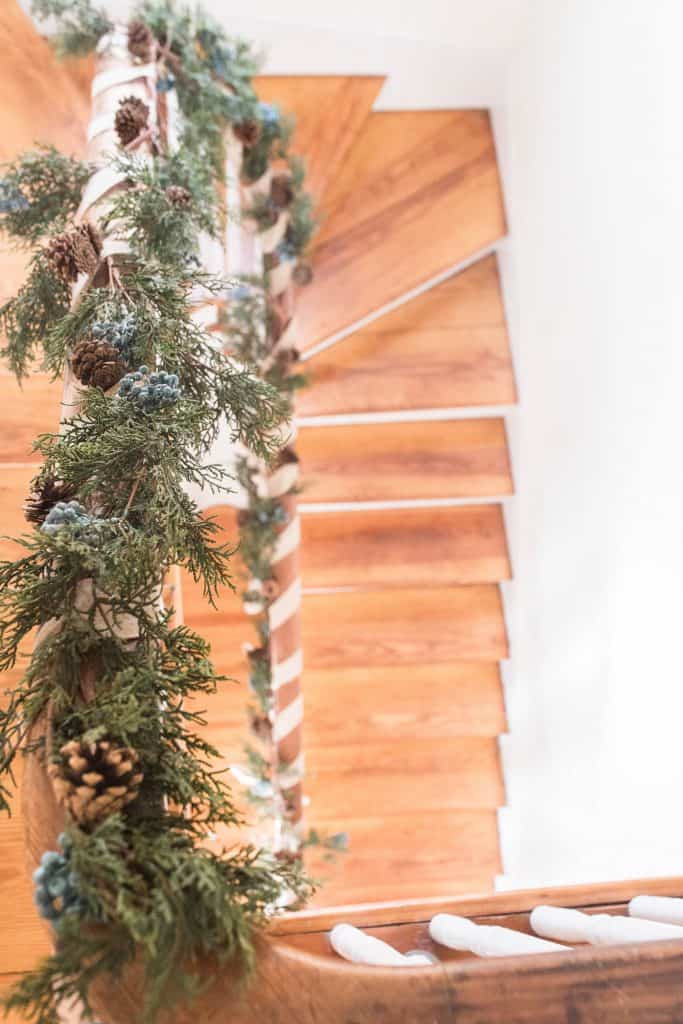 view from the top of the stair looking down to the bottom with the banister wrapped in greenery