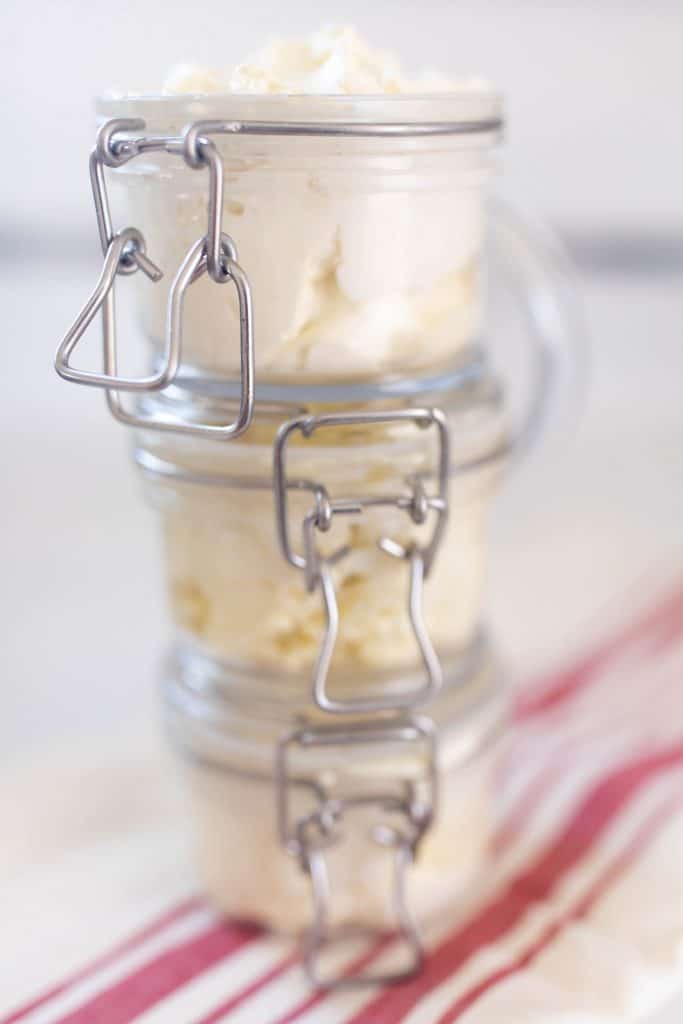 gingerbread whipped body butter in glass jars stacked up three high on a cream and red stripped towel
