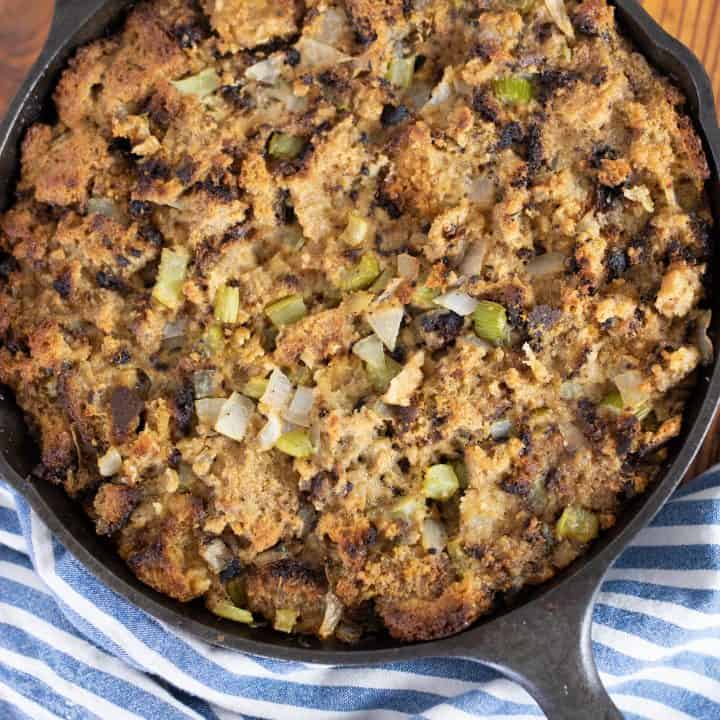 homemade sourdough stuffing from scratch in a cast iron skillet on top a blue and white stripped towel