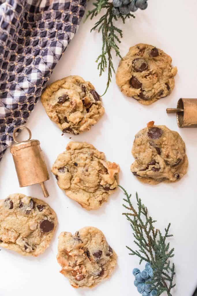 toasted coconut cookies on a white countertop with bells and greenery spread out around the cookies