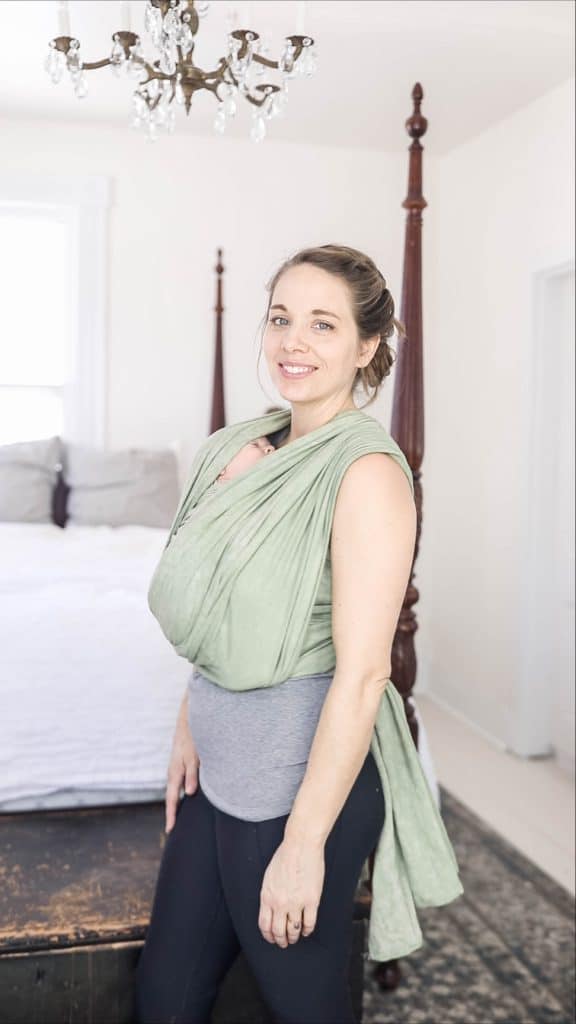 Women baby wearing with a green woven wrap