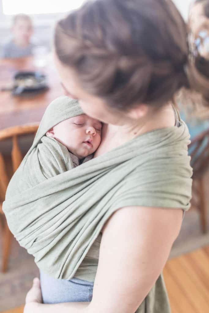 women wearing a baby in a green woven wrap 