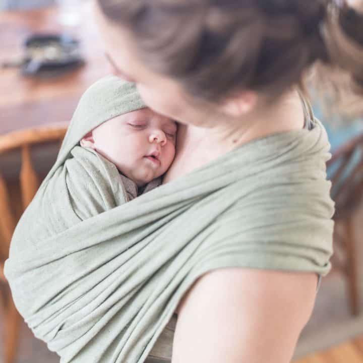 women wearing a baby in a green woven wrap