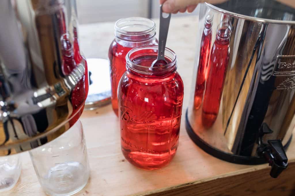 adding red dye to two half gallon mason jars to preform the Berkey red dye test.