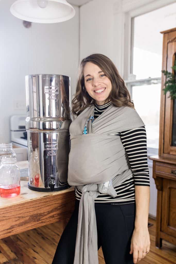 women wearing a baby standing next to a Berkey Water filter smiling