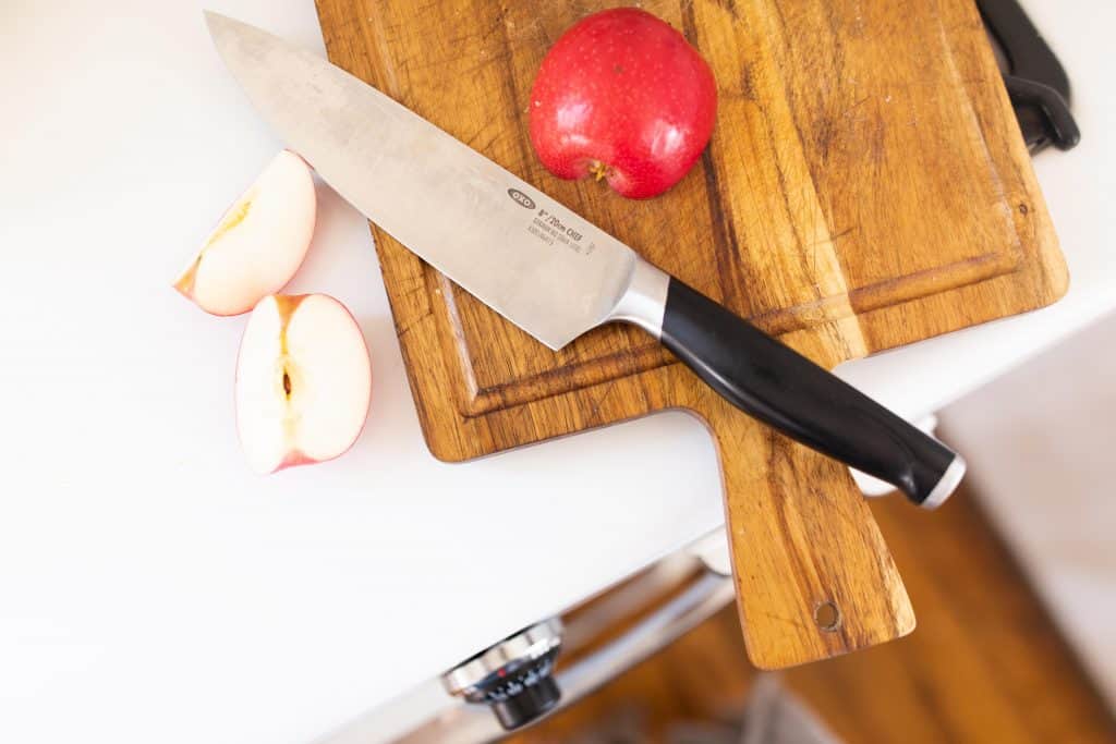 cutting apples on a wood cutting board with a chefs knife