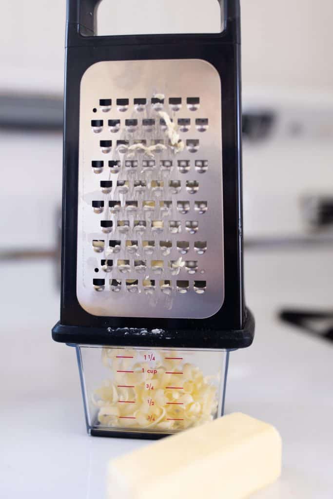 frozen butter being grated using a cheese grater with plastic container