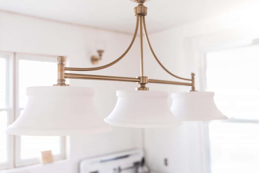 beautiful brass light fixture with three glass lamps in a victorian farmhouse