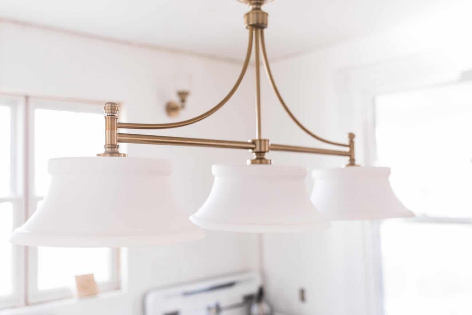 beautiful brass light fixture with three glass lamps in a victorian farmhouse