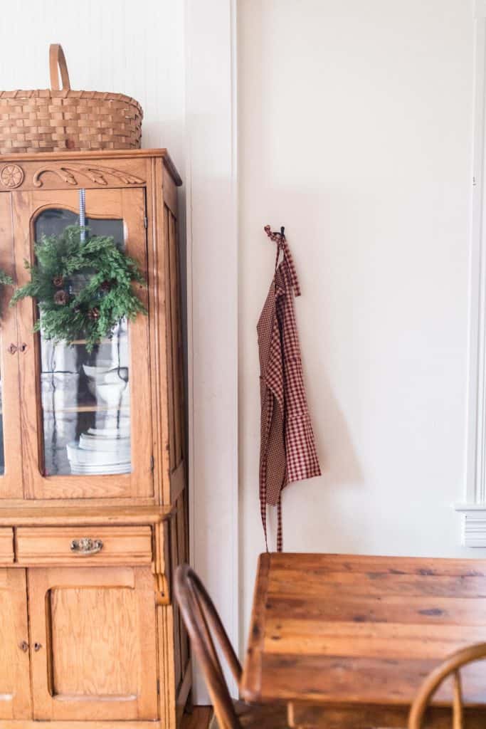 diy reversible apron hanging on a hook next to a wood China cabinet