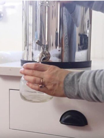 women filling a mason jar of filtered water from a Berkey water filter
