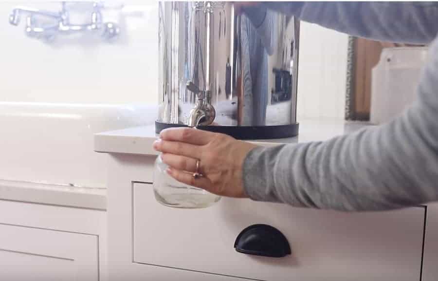 women filling a mason jar of filtered water from a Berkey water filter