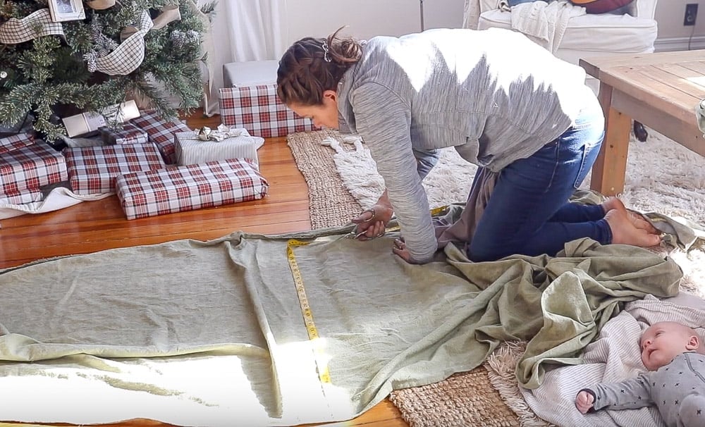 women wearing gray sweatshirt on the floor measuring and cutting fabric