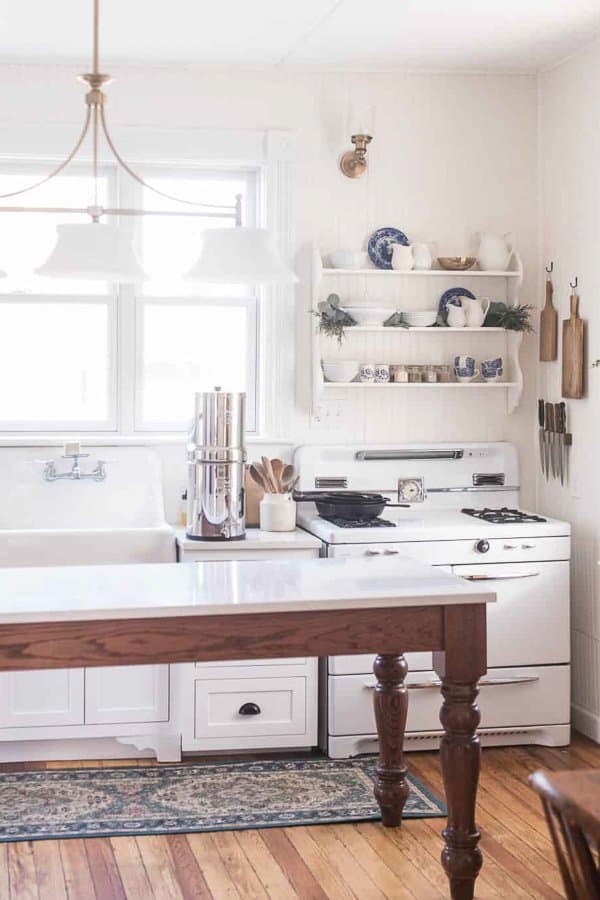 farmhouse kitchen organization with open shelves above antique stove with cutting boards and knives hanging to the right