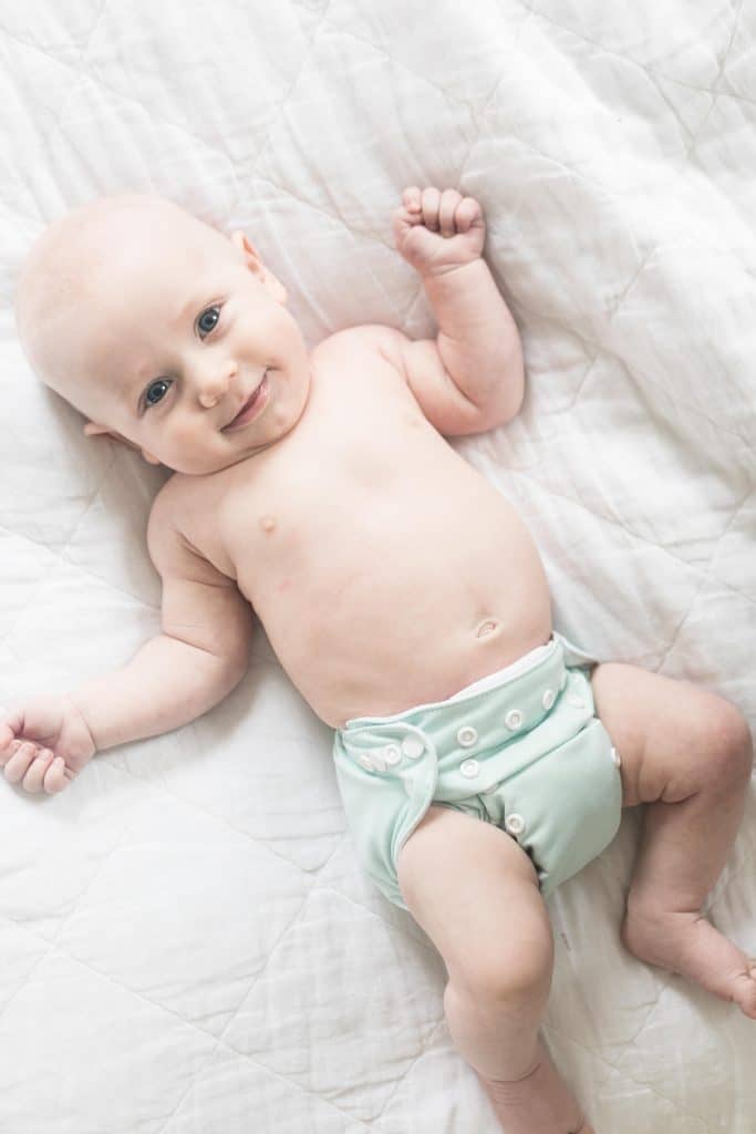 smiling newborn baby wearing Alva newborn diapers