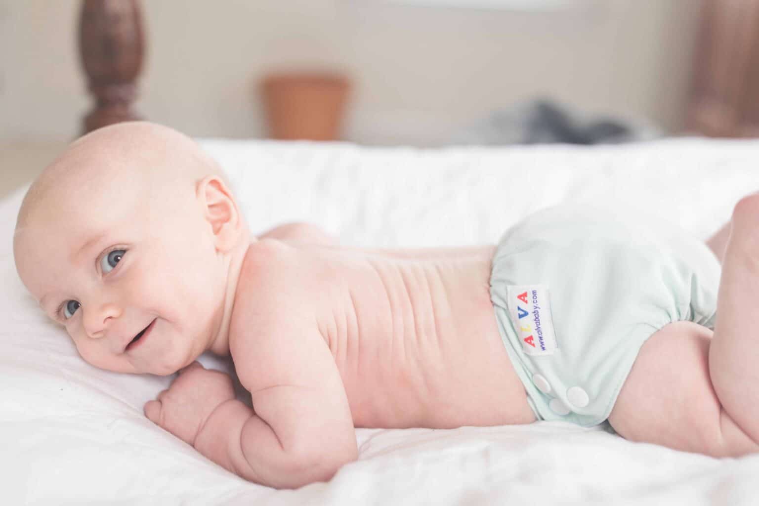 baby wearing cloth diaper on his belly holding his head up