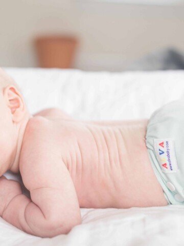 baby wearing cloth diaper on his belly holding his head up