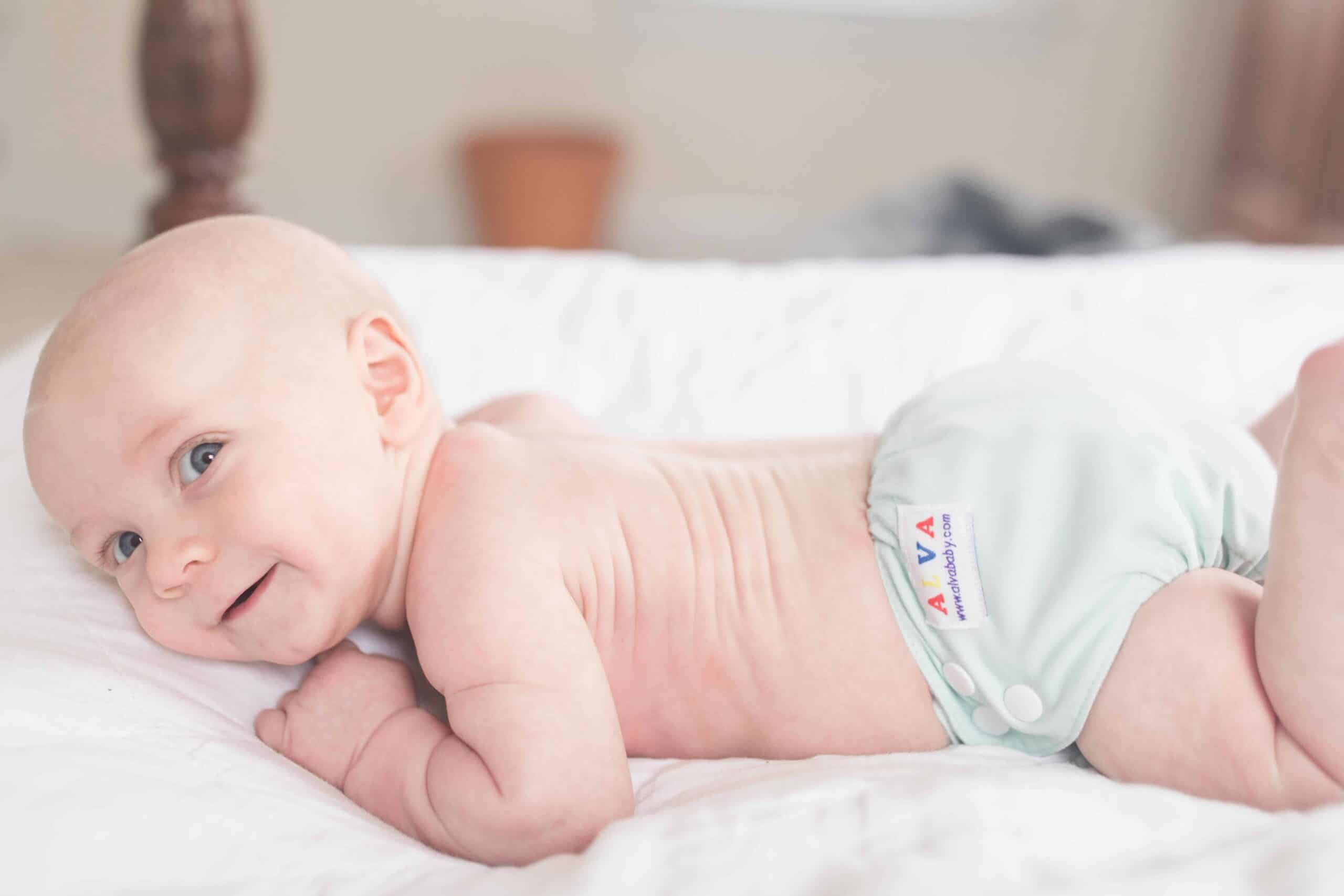 baby wearing cloth diaper on his belly holding his head up