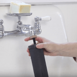 hand placing Black Berkey filter element onto running faucet to prime the filters