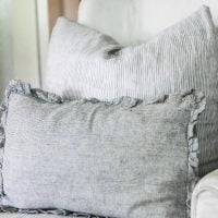 gray DIY ruffle pillow cover on a chair with a large pillow behind it.