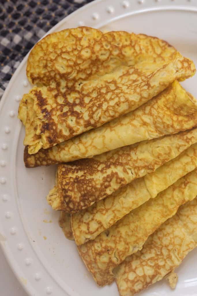 sourdough crepes rolled up on a white plate