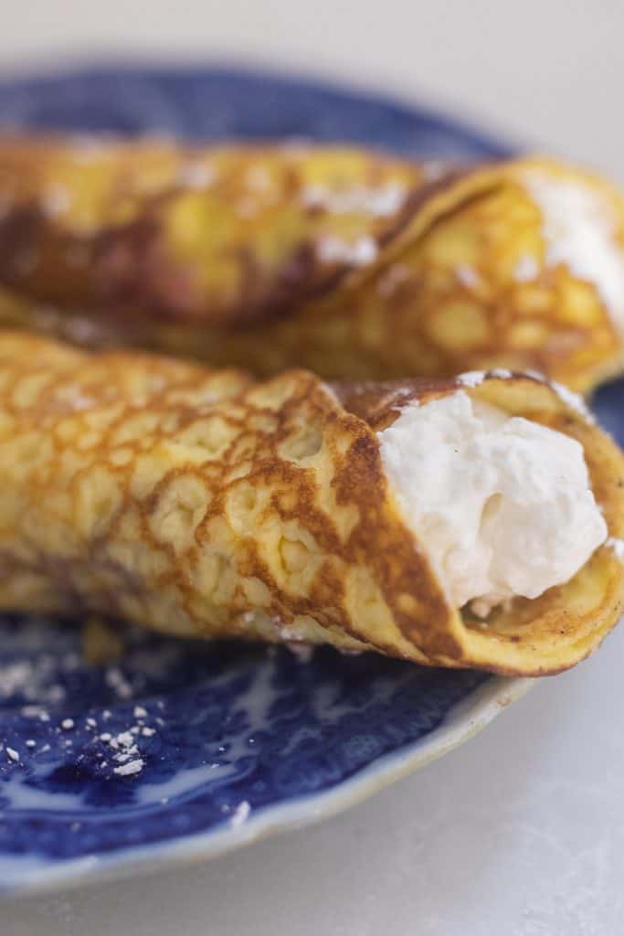 two sourdough crepes with whipped cream cheese filling on a vintage blue plate.