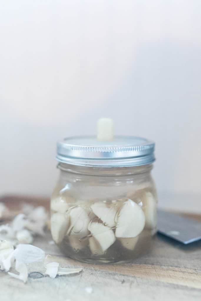 peeled whole garlic cloves in a jar with a fermenting lid - making fermented garlic